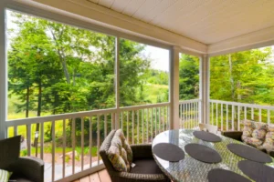 Screen room overlooking a wooded area with table and chairs in the foreground.